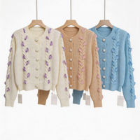 Cardigan court en maille torsadée pour femme, col rond, orné de perles en forme de pétale violettes, par le fabricant Cream Cable