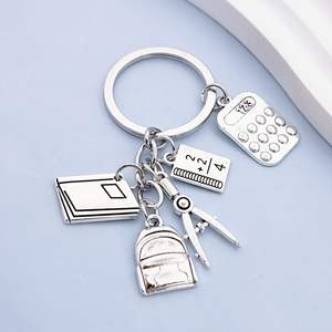 Accessoires de mode : Mini <span class=keywords><strong>sac</strong></span> <span class=keywords><strong>à</strong></span> <span class=keywords><strong>dos</strong></span> pendentif en métal étanche, motif dessin animé, avec calculatrice, règle et livre – Cadeau <span class=keywords><strong>pour</strong></span> la Fête des Enseignants et le début du nouveau semestre - Product Image 1