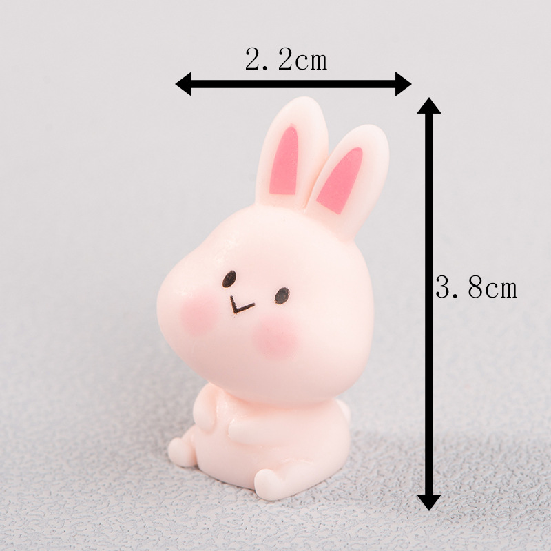 Assis, les bras croisés autour du ventre, rose.