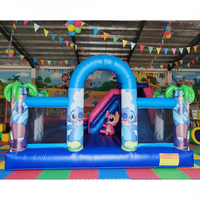 Château gonflable bleu vif avec toboggan et personnage de dessin animé ludique pour le divertissement des enfants en intérieur