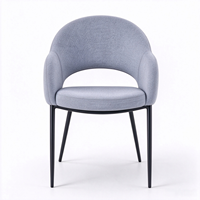 Fauteuil moderne en tissu gris clair avec dossier découpé unique et pieds en métal noir pour salon ou salle à manger