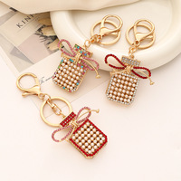 Porte-clés pendentif exquis en métal avec nœud, pompon, perle et flacon de parfum, petit cadeau