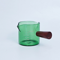 Vaso medidor de vidrio verde de 75 ml / 2.2 oz con un solo mango de madera para extractos de sabor, alimentos, concentrados de café y bebidas espirituosas.