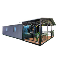 Maisonnette préfabriquée moderne en acier avec porche à pignon, portes vitrées, terrasse en bois, guirlandes lumineuses, maison de vacances pour jardin