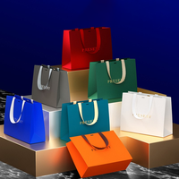Sac shopping personnalisé en papier métallisé argenté avec logo noir et larges poignées en ruban de satin noir pour vêtements de luxe