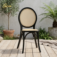 Chaise de banquet de mariage à dossier médaillon, cadre noir classique avec assise en rotin naturel pour la location d'événements hôteliers