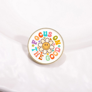 Spilla smaltata creativa con citazione positiva "Focus on the Good" e faccina sorridente floreale, per decorazione di zaini, cappelli e abbigliamento - Product Image 1