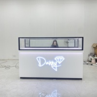 Comptoirs en verre trempé transparent avec éclairage LED et cadre en acier inoxydable durable, personnalisables pour l'aménagement de toute une boutique, usage commercial
