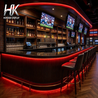 Ensemble de mobilier de bar personnalisé avec comptoir en L, étagères à bouteilles, banquette et vitrine en verre pour bar sportif