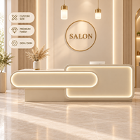 Comptoir d'accueil moderne pour salon de beauté, beige crème, asymétrique, double couche, façade arrondie avec éclairage LED chaud pour hall de spa