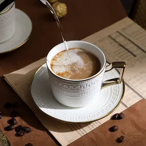 Avrupa öğleden sonra çay kullanılan zarif kabartma tasarım beyaz seramik latte çay bardağı ve altlık altın jant kahve fincan seti