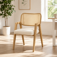 Chaise de salle à manger à bras angulaires avec dossier en rotin suspendu et assise rembourrée sur structure à grain clair pour salle de bain et atelier