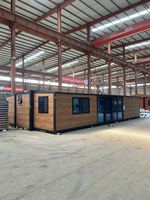 Cabine conteneur préfabriquée de 20 pieds avec revêtement imitation bois et entrée centrale en verre pour projets de maisons d'hôtes modulaires
