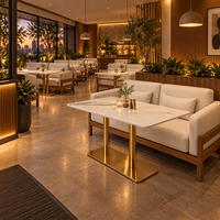Ensemble de canapés de restaurant de style côtier moderne, chaises et tables, canapé en chêne clair avec coussins crème et table en marbre blanc avec pieds dorés