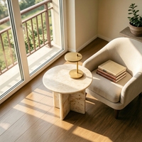 Table basse en marbre travertin beige à pieds croisés, style moderne et organique, idéale pour l'aménagement intérieur Japandi et les cafés chaleureux