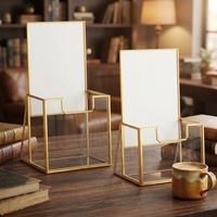 Présentoir minimaliste en fil doré avec base ouverte pour brochures, cartes et petites impressions d'art sur comptoir