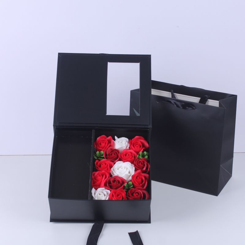 Boîte d'emballage noire avec sac à main et fleur
