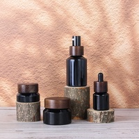 Flacon en verre noir à épaules arrondies avec couvercle en bois pour l'emballage des soins de la peau, des lotions et des shampoings