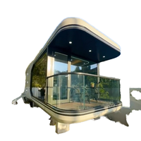 Cabane modulaire suspendue sur la falaise, surélevée sur des échasses, avec vue panoramique sur la montagne, type capsule spatiale