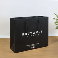 Sacs en papier noir enduit avec logo blanc imprimé sur mesure haut de gamme pour l'emballage de cadeaux et les soins personnels