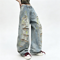 Jean long en denim style rétro américain, coupe courbée, effet vieilli et déchiré avec trous, peint avec des graffitis colorés