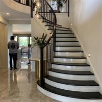 Escalier de luxe en bois courbé pour villas durable avec garde-corps en fer forgé et bandes de roulement en chêne massif fabriqué sur mesure à Foshan