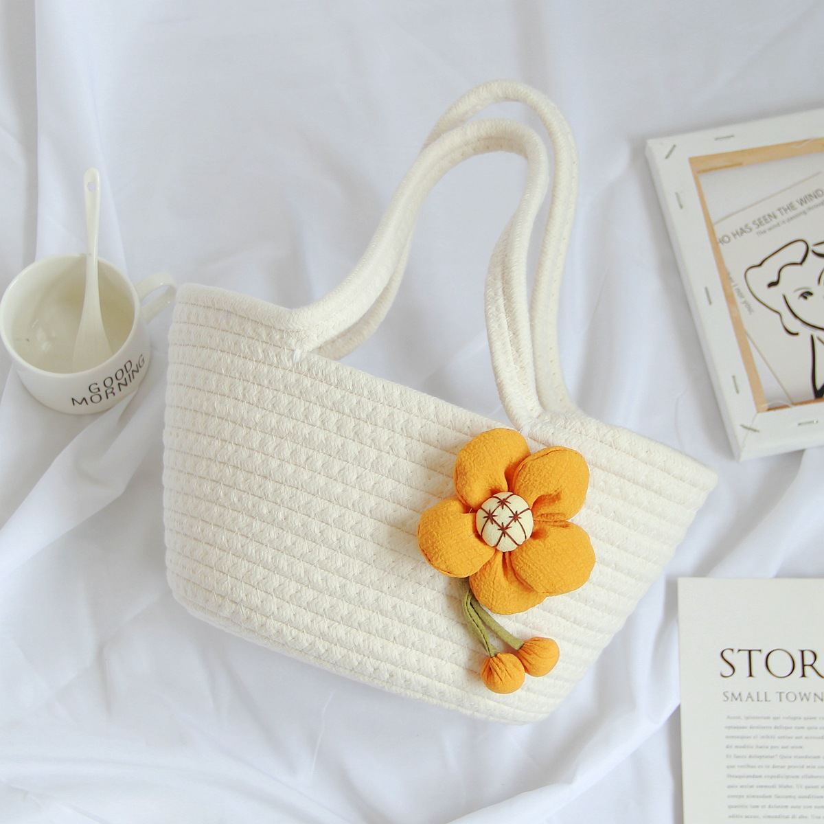 Borsa a mano color bianco latte con motivo floreale.