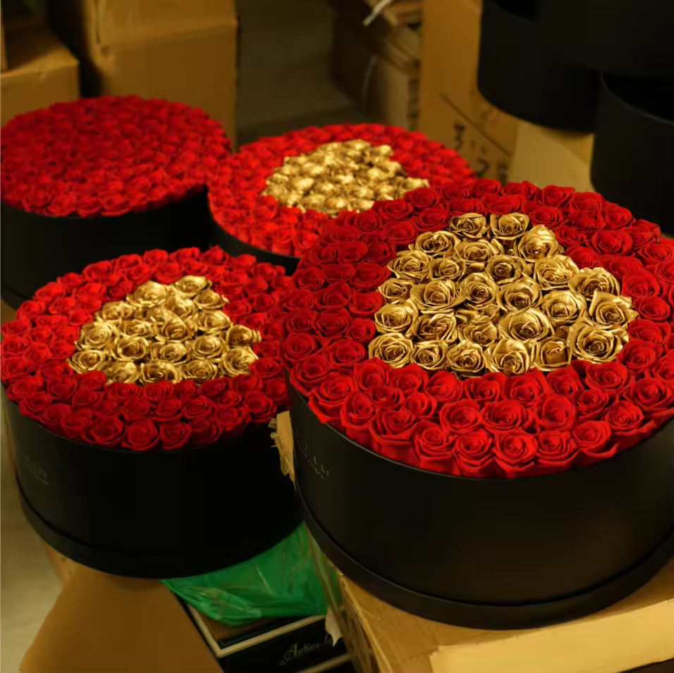 Boîte ronde de 52 roses rouges avec roses dorées