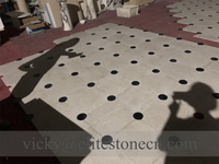 Carrelage de sol en pierre calcaire beige avec points noirs en forme d'échiquier