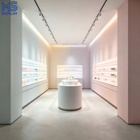 Comptoir d'îlot ovale personnalisé pour magasin de cosmétiques avec éclairage LED et étagère murale multi-niveaux pour boutique de cosmétiques
