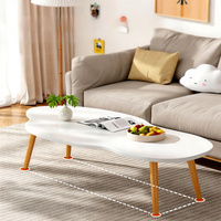 Table basse moderne et simple avec pieds en bois massif et plateau en panneau de densité, forme irrégulière, idéale pour les petits appartements et salons.