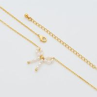 Collier de luxe en cuivre avec nœud papillon et perles d'imitation, design unique, sensation haut de gamme, tendance et polyvalent pour femme