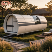 Capsule habitable avec chambre, salon, salle de bain, fenêtre incurvée en verre, lucarne, coque blanche, cadre foncé, maison capsule préfabriquée