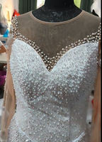 Robe de mariée sirène de luxe blanche perlée 2026 avec encolure illusion transparente, manches longues et traîne volumineuse à volants