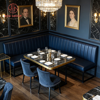 Ensemble de chaises de banquettes en velours bleu foncé européen avec table en marbre à bordure dorée et structure métallique pour salle à manger, café, restaurant, hôtel