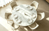 Table à manger élégante et minimaliste en marbre Arabescato à plateau rond et piétement unique, idéale pour les maisons modernes à plan ouvert