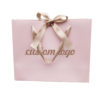 Sac cadeau en papier rose pâle personnalisé avec poignées en satin et nœud en satin pour les entreprises et la vente au détail de vêtements en marque privée