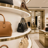 Vitrine de présentation de sacs à main en acier inoxydable doré de luxe sur mesure avec éclairage LED incurvé pour boutique de détail