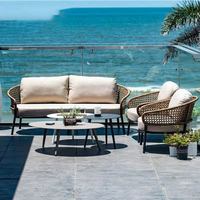 Ensemble de meubles de balcon et de patio en rotin naturel, canapé deux places, fauteuils, table basse ovale, tables d'appoint, coussin beige, pieds en métal
