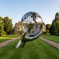 Grande sculpture de globe terrestre creux en acier inoxydable poli miroir, en forme de main tenant un globe, pour l'aménagement paysager des places universitaires