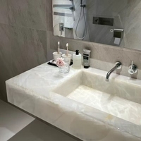 Dalles de marbre blanc translucide en onyx cristallin de l'ère glaciaire avec surface polie pour éviers de salle de bain d'hôtels modernes