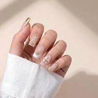 Faux ongles à presser carrés moyens, blancs nude, diagonaux, style French, en acrylique, couvrance totale, avec ligne de paillettes or rose, courts