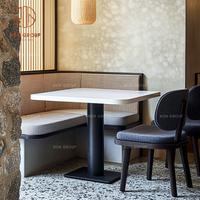 Ensemble complet de meubles de restaurant commercial Ron Group : tables en marbre, chaises bleues rembourrées, banquettes.