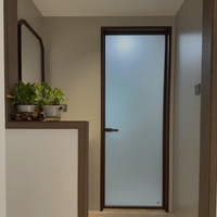 Porte de salle de bain minimaliste standard à charnières avec cadre en alliage titane-magnésium et panneaux en verre dépoli pour toilettes intérieures d'hôtel