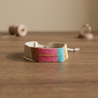 Pulsera de algodón tejida a mano Sstringz, detalles de cuentas en color blanco marfil, rosa intenso, azul turquesa y dorado, ajustable.
