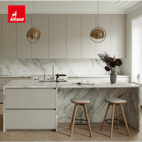Cuisine Alland moderne et minimaliste, avec panneaux plats mats couleur crème personnalisés, îlot et plan de travail en marbre blanc.