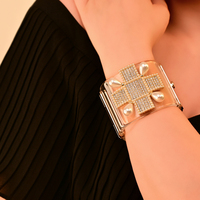 Bracelet jonc audacieux pour femme, imitation perles et cloutages dorés, style punk, bijou statement avec design manchette et bracelet de montre