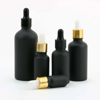 Flacon compte-gouttes cylindrique en verre noir mat personnalisé avec logo, bouchon doré/noir, pour huiles essentielles, sérums et cosmétiques – Vente en gros