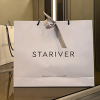 Sac cadeau élégant en papier blanc avec intérieur noir, poignée en corde, logo de la marque pour magasin de vêtements