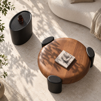 Ensemble de tables basses en forme de galet avec plateau en bois arrondi et trois pieds épais noirs pour salons modernes et organiques